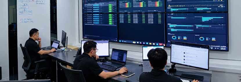 Pasukan memantau rangkaian di depan skrin, gambar dari kulit prospektus. Impact mula tawar servis rangkaian terurus dengan pusat operasi rangkaian (NOC) sendiri pada 2023. NOC tu kini dikendalikan Voculus, yang masuk Kumpulan pada Januari 2024, di ICOM Square, Kuching. Prospektus tak nyatakan lokasi gambar ni.