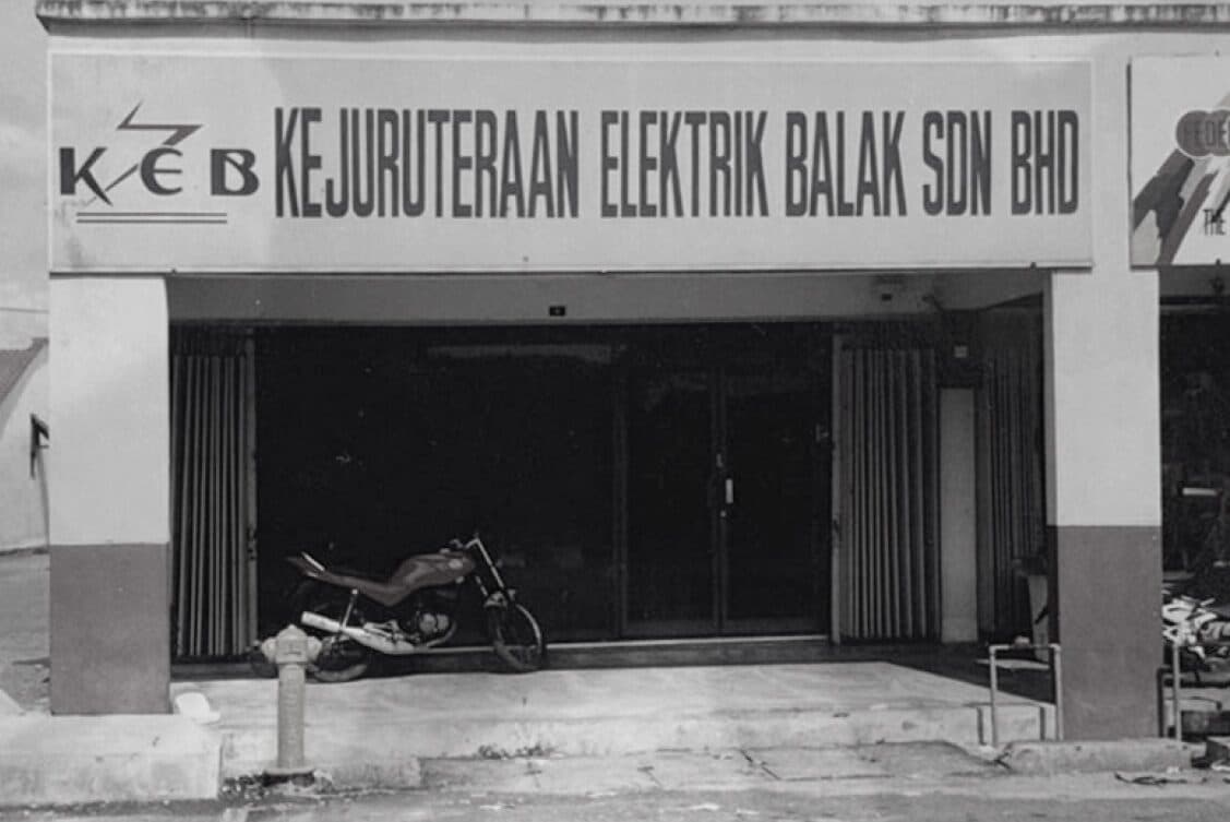 Gambar lama dari halaman sejarah laman web KEB bertanda 1993: papan tanda 'Kejuruteraan Elektrik Balak Sdn Bhd'. Prospektus catat Datuk KC Lim mula sebagai juruteknik elektrik dan, pada 1993, tubuhkan KEB Ventures Sdn Bhd untuk kerja kabel bawah tanah, yang dia lepaskan pada 2011 dan 2015. Prospektus tak terangkan asal nama KEB.
