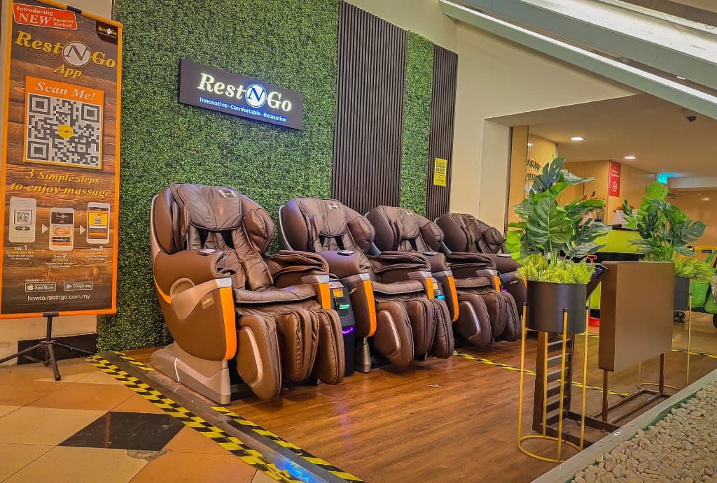 Stesen Rest N Go di Sunway Pyramid — kerusi urut layan diri yang jadi teras bisnes RNG Tech. Standee di sisi ajak pengguna imbas kod QR dan ikut tiga langkah sebelum sesi bermula.